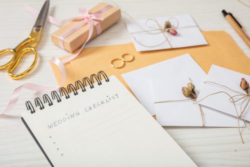 Flat lay and close up view of checklist and wedding invitations